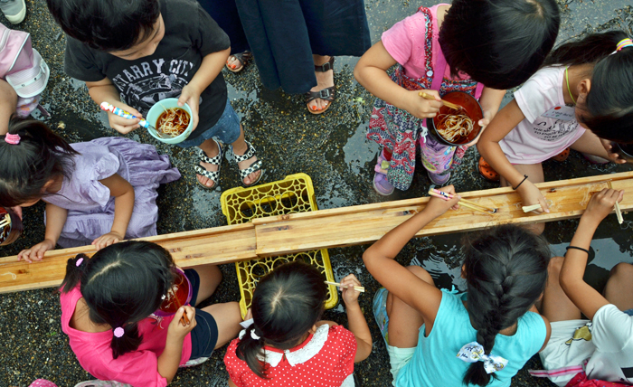 Children enjoy Nagashi Somen at an outdoor party.